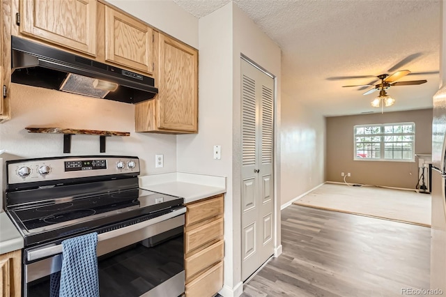 kitchen with stainless steel electric stove, a textured ceiling, under cabinet range hood, ceiling fan, and light brown cabinetry