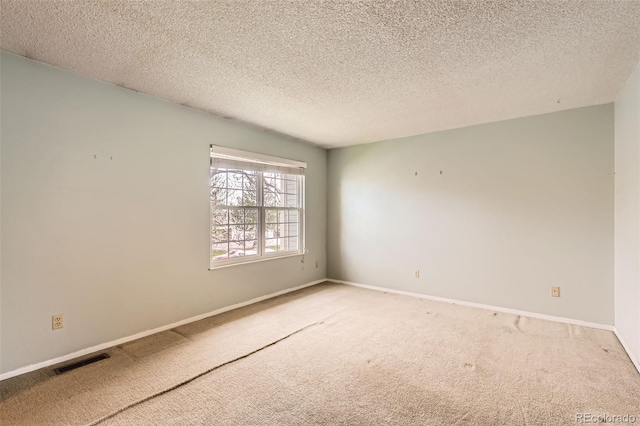 carpeted empty room with a textured ceiling, baseboards, and visible vents