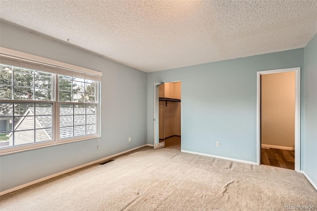 unfurnished bedroom featuring baseboards, carpet flooring, visible vents, and a textured ceiling