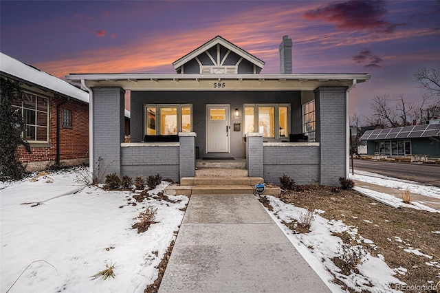 bungalow-style house featuring a porch and brick siding