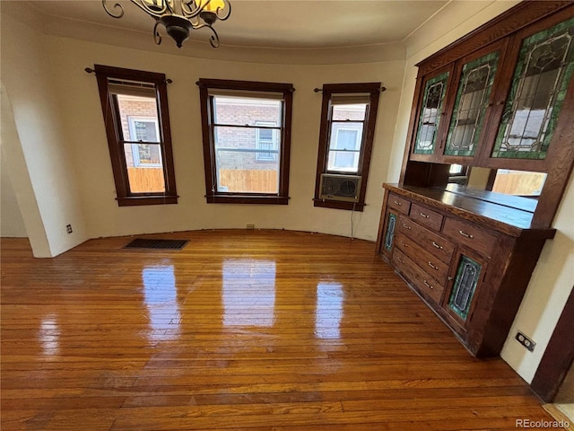 unfurnished dining area with cooling unit, hardwood / wood-style floors, and a chandelier