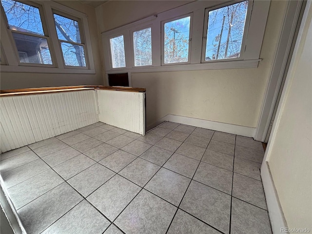 spare room featuring light tile patterned flooring and baseboards