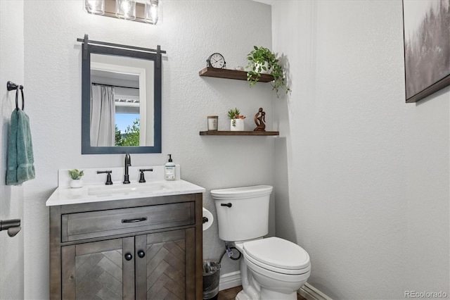 bathroom with baseboards, toilet, and vanity