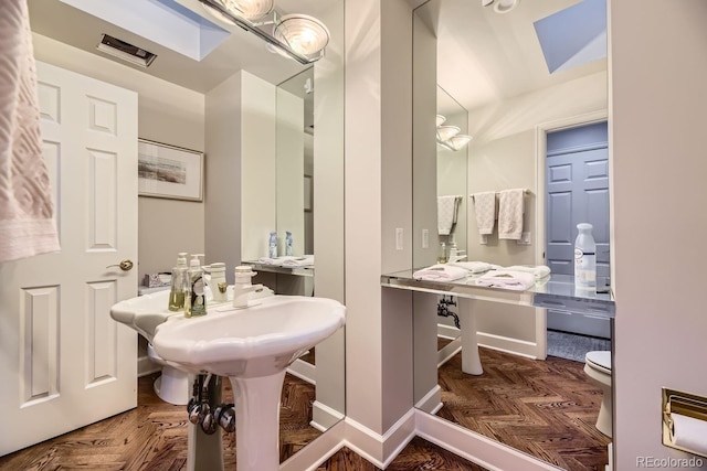 bathroom featuring parquet flooring and toilet