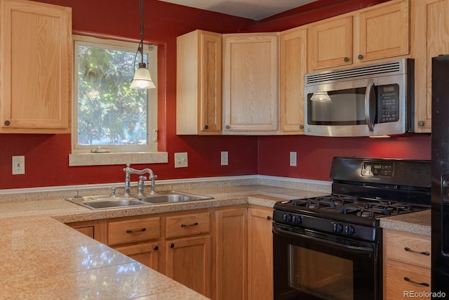 kitchen featuring black gas range, decorative light fixtures, light brown cabinetry, and sink