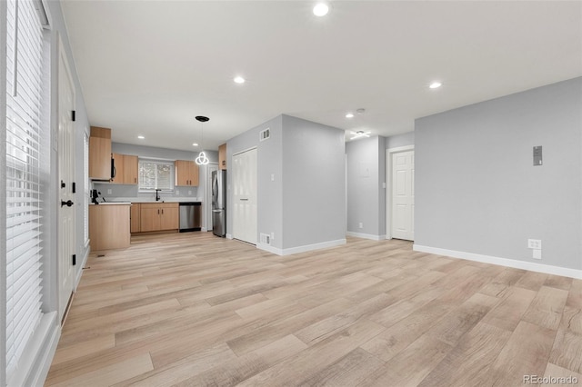 unfurnished living room featuring light hardwood / wood-style flooring and sink