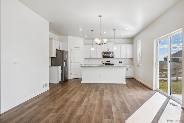 kitchen with white cabinetry, an island with sink, stainless steel appliances, and decorative light fixtures