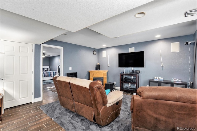 living area with dark wood finished floors, baseboards, a warm lit fireplace, recessed lighting, and ceiling fan