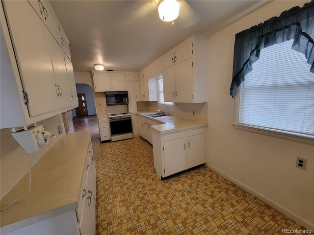 kitchen with white cabinetry, ceiling fan, sink, and white stove