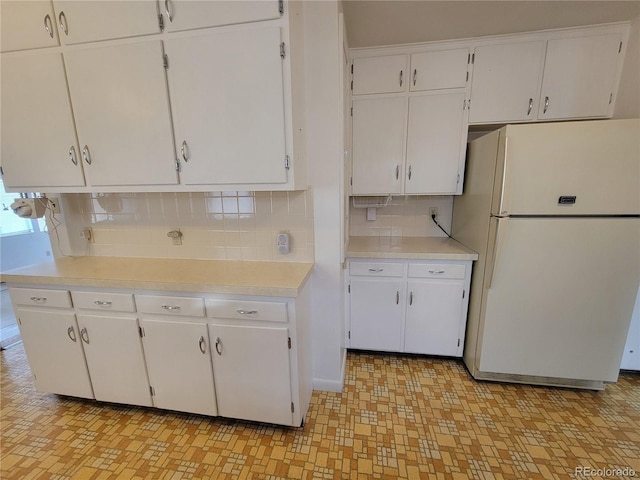 kitchen with white fridge, tasteful backsplash, and white cabinets