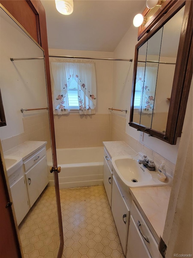 bathroom featuring vanity, plus walk in shower, and tile walls