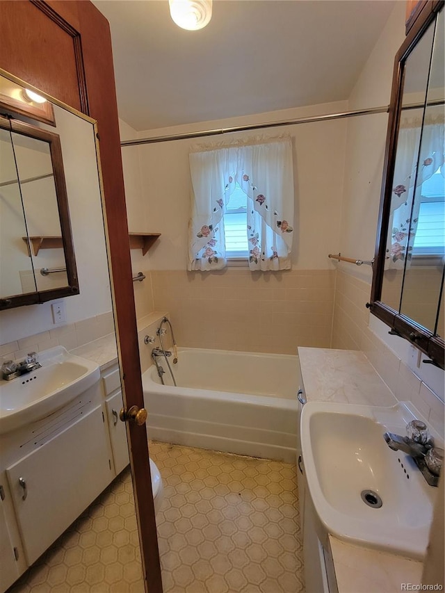 bathroom featuring vanity, tile walls, a bath, and a wealth of natural light