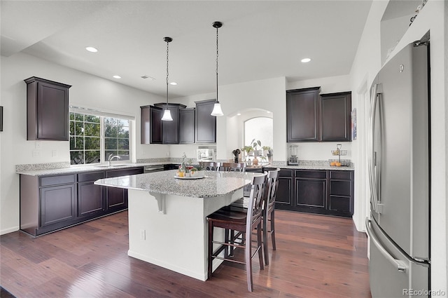 kitchen featuring stainless steel refrigerator, a kitchen breakfast bar, a kitchen island, sink, and dark hardwood / wood-style floors