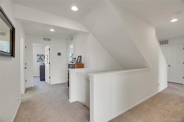 hall with light carpet and vaulted ceiling