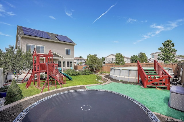 exterior space with a fenced in pool, a playground, a lawn, and solar panels