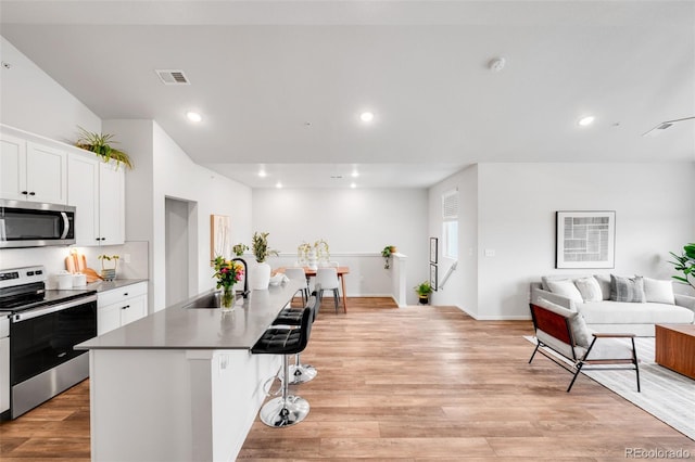 2080 Autumn Moon Dr Unit 5, Windsor, CO 80550 - kitchen featuring stainless steel appliances, open floor plan, a breakfast bar area, white cabinets, and decorative backsplash