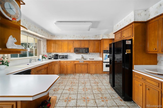 kitchen featuring brown cabinets, light countertops, wallpapered walls, and black appliances