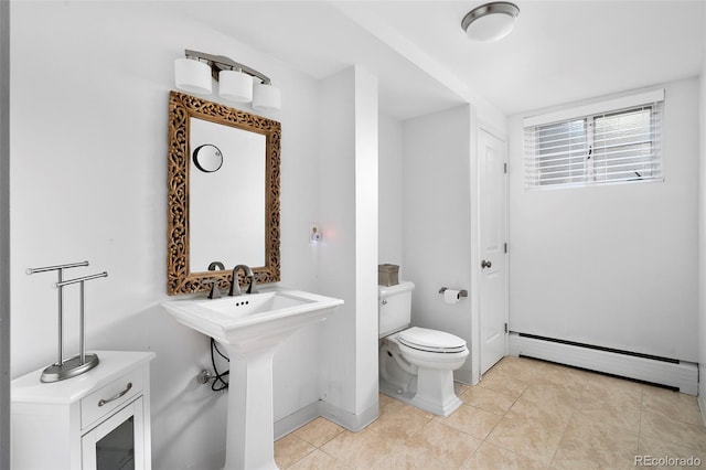 bathroom with tile patterned floors, baseboard heating, baseboards, toilet, and a sink