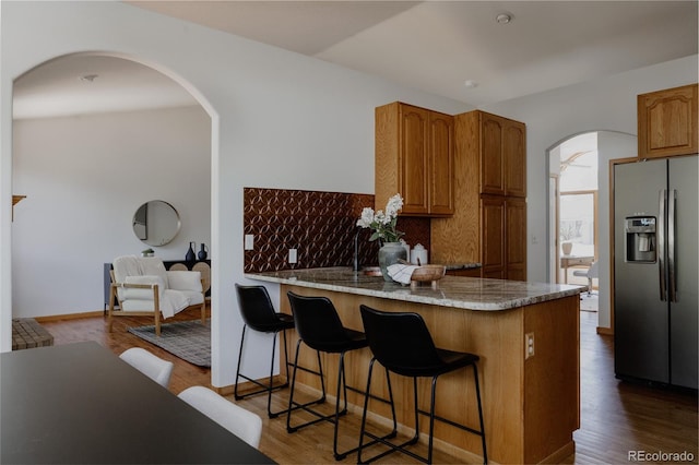 1131 N 4th St, Johnstown, CO 80534 - kitchen featuring refrigerator with ice dispenser, arched walkways, a peninsula, tasteful backsplash, and dark wood-style flooring