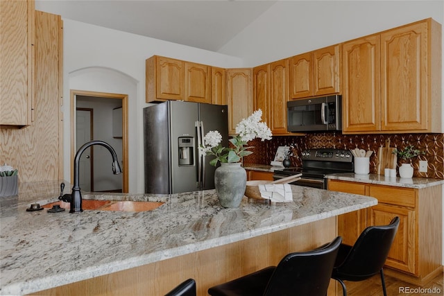 1131 N 4th St, Johnstown, CO 80534 - kitchen with appliances with stainless steel finishes, decorative backsplash, a breakfast bar area, vaulted ceiling, and light stone countertops