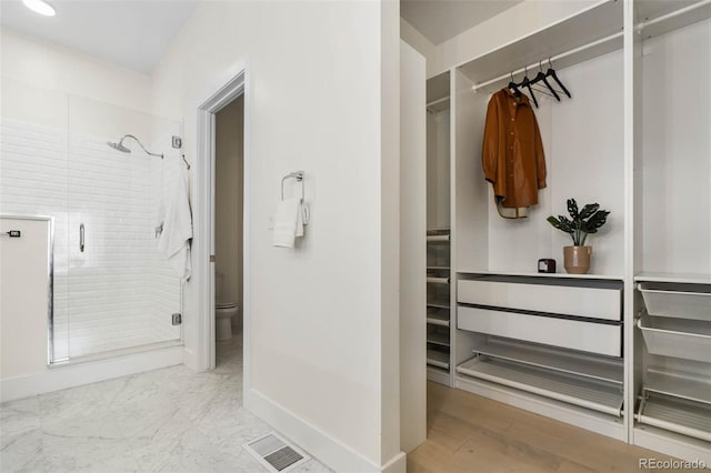 bathroom featuring toilet, visible vents, a stall shower, and baseboards