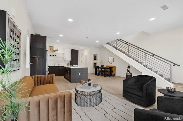 living area featuring visible vents, recessed lighting, light wood-type flooring, and stairs