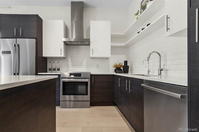 kitchen with stainless steel appliances, tasteful backsplash, wall chimney exhaust hood, and light countertops