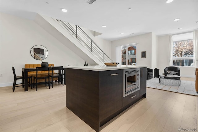 kitchen with stainless steel microwave, light wood-type flooring, light countertops, plenty of natural light, and modern cabinets