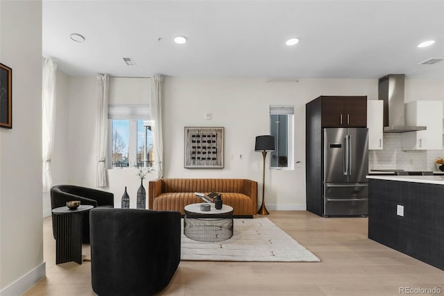 living room with recessed lighting, visible vents, light wood-style flooring, and baseboards