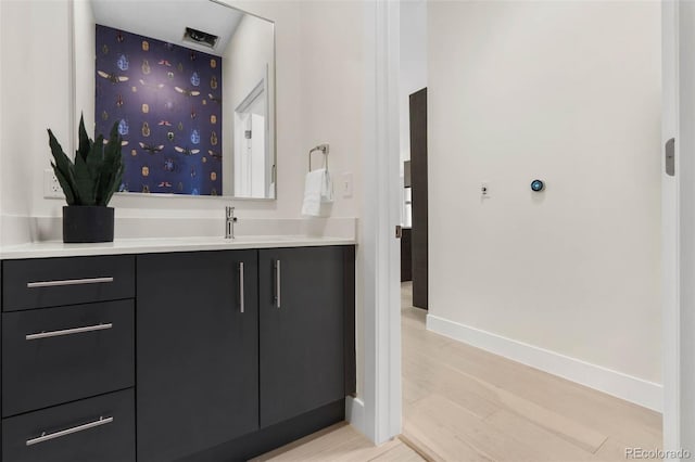 bathroom featuring baseboards, wood finished floors, and vanity