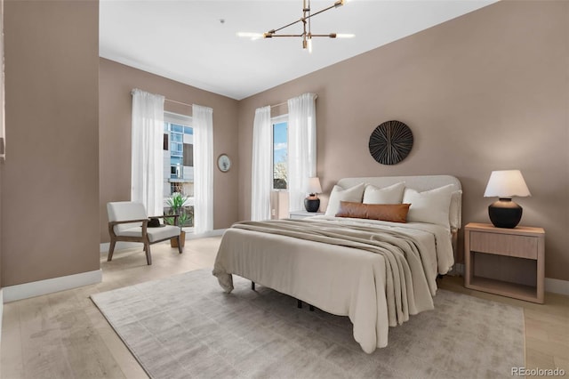 bedroom featuring a notable chandelier, baseboards, and light wood-style floors