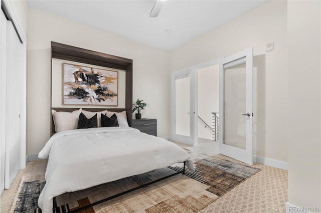 bedroom featuring french doors, a closet, baseboards, light colored carpet, and ceiling fan