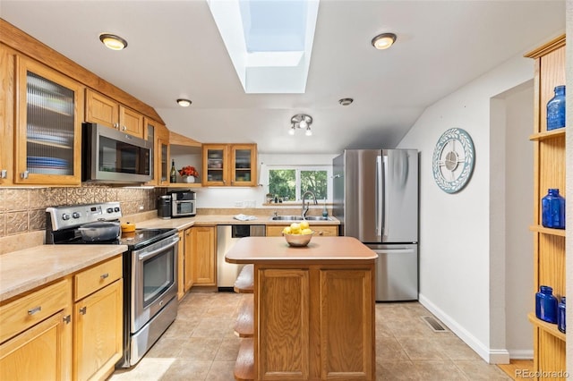 6480 W 60th Ave, Arvada, CO 80003 - kitchen featuring appliances with stainless steel finishes, a skylight, a sink, light countertops, and a center island