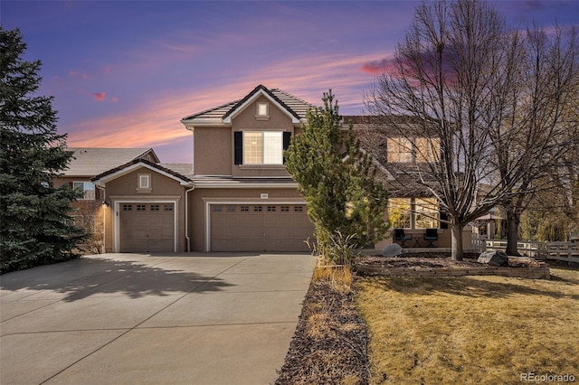 traditional-style house featuring stucco siding, driveway, a tile roof, fence, and an attached garage