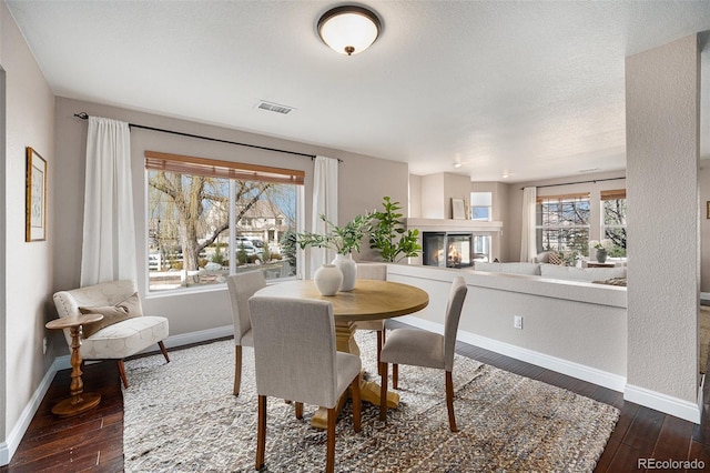 dining area with dark wood finished floors, a healthy amount of sunlight, and visible vents