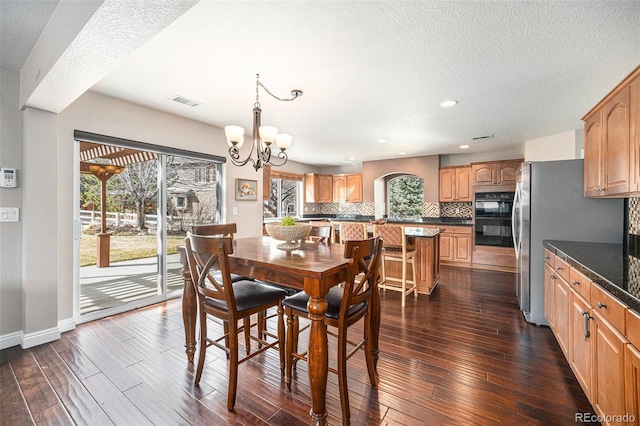 dining area featuring a chandelier, baseboards, a textured ceiling, and dark wood finished floors