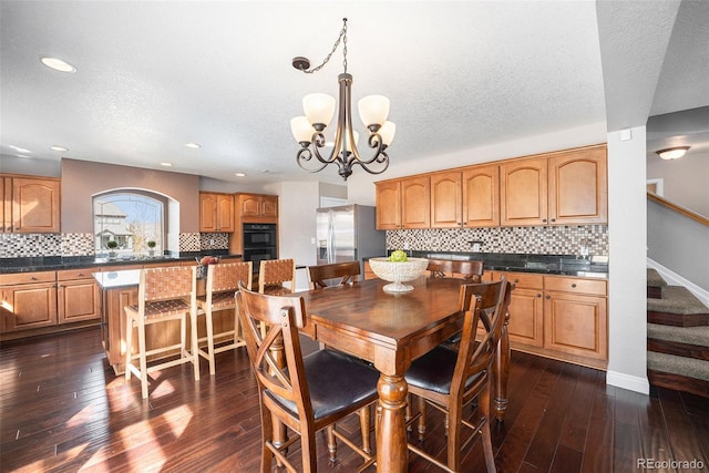 dining area with dark wood-type flooring, a textured ceiling, stairway, an inviting chandelier, and baseboards