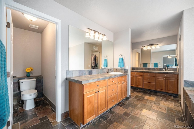 bathroom featuring stone tile floors, visible vents, baseboards, and a sink