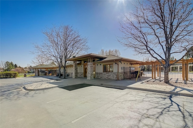 view of front of house with stone siding, a fenced front yard, and stucco siding