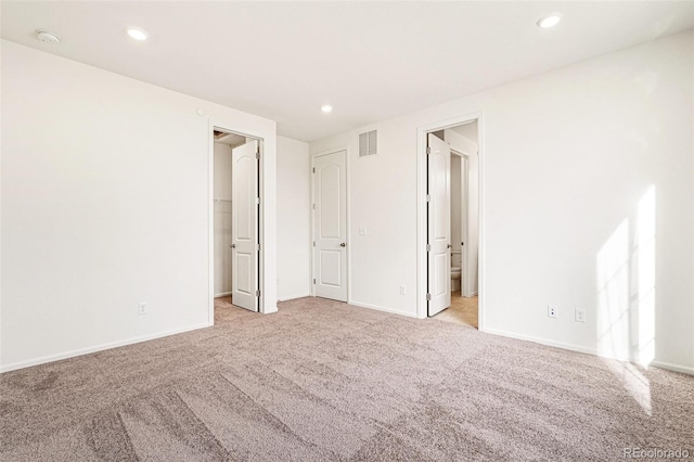 unfurnished bedroom with ensuite bath and light carpet