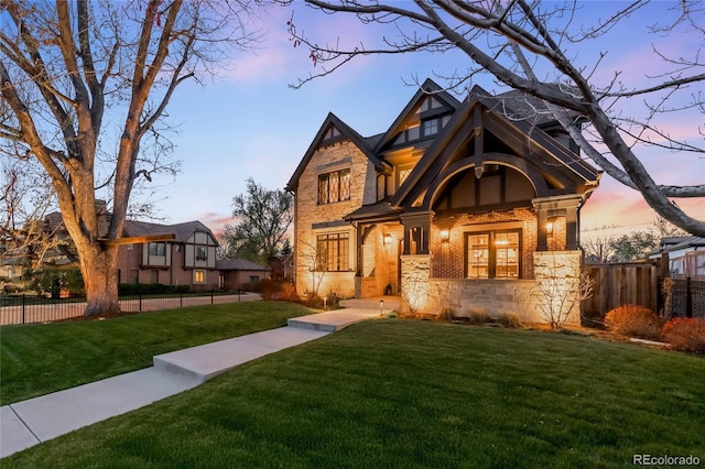 view of front of house with fence, stone siding, and a front lawn