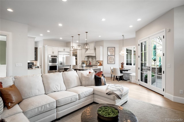living area featuring recessed lighting, baseboards, and light wood-type flooring