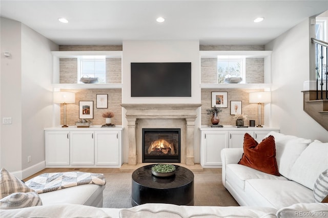 living room featuring a premium fireplace, recessed lighting, a healthy amount of sunlight, and light wood-style flooring