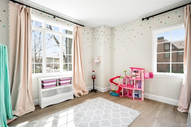 playroom featuring baseboards, wood finished floors, and a wealth of natural light