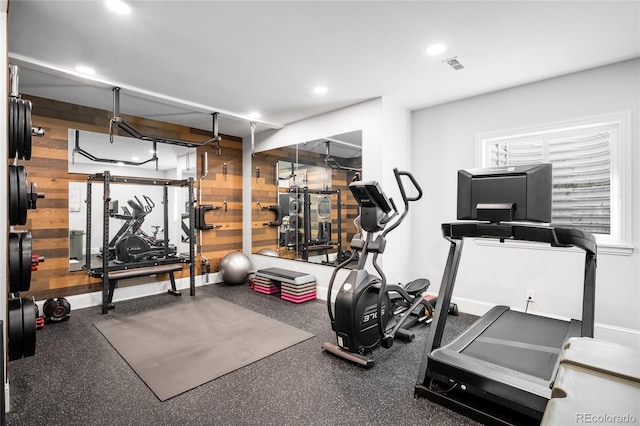 exercise room featuring wooden walls, baseboards, recessed lighting, and visible vents