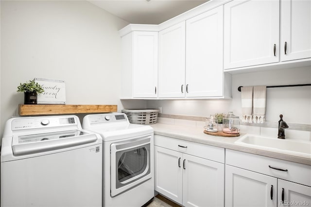 washroom featuring a sink, separate washer and dryer, and cabinet space