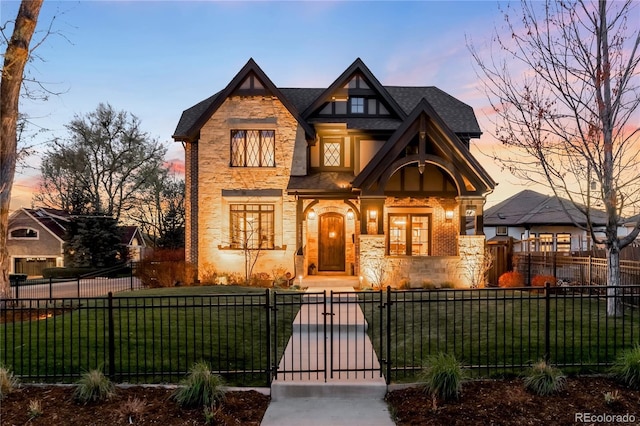 view of front of home featuring a fenced front yard, roof with shingles, a gate, a yard, and stone siding