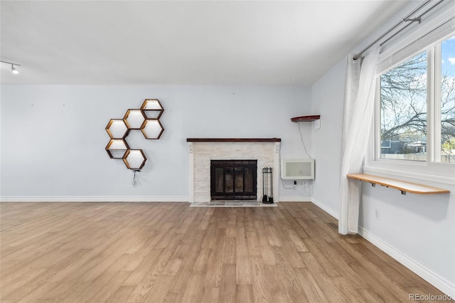 4860 S Field Way, Littleton, CO 80123 - unfurnished living room with wood finished floors, a fireplace with flush hearth, rail lighting, and an AC wall unit