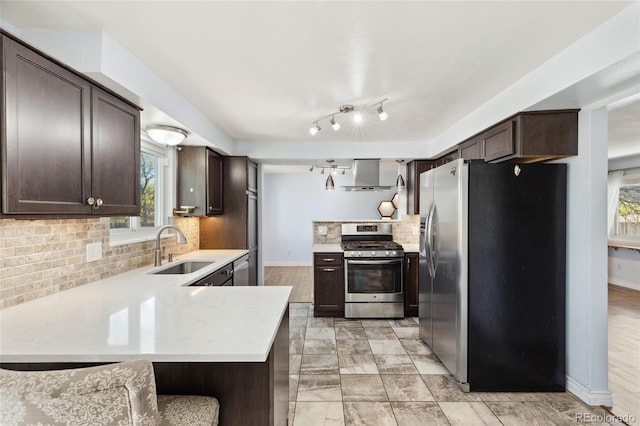 4860 S Field Way, Littleton, CO 80123 - kitchen featuring stainless steel appliances, wall chimney range hood, dark brown cabinetry, and a peninsula