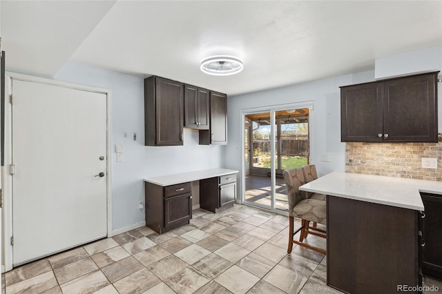 4860 S Field Way, Littleton, CO 80123 - kitchen featuring dark brown cabinets, light countertops, tasteful backsplash, built in desk, and a kitchen breakfast bar
